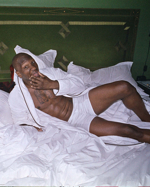 Marcus laying in bed wearing Boxer Shorts in White