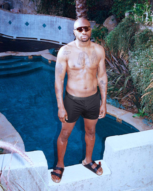 Marcus standing by the pool wearing moisture wicking Boxer Shorts in Black