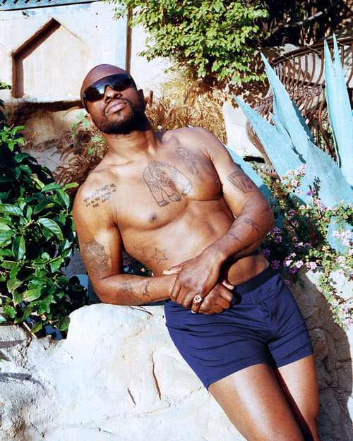 Marcus standing outside in the sun wearing sunglasses and Boxer Shorts in Navy Blue