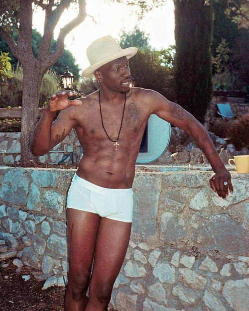 Marcus standing outside wearing Boxer Trunk in White and a straw hat
