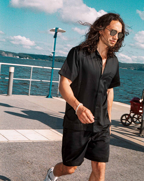 Oskar walking by the water wearing Home Shorts in Black