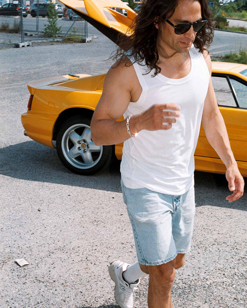 Oskar walks in the parking lot wearing Tank Top in white