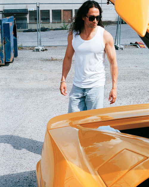 Oskar standing by the car wearing Tank Top in White
