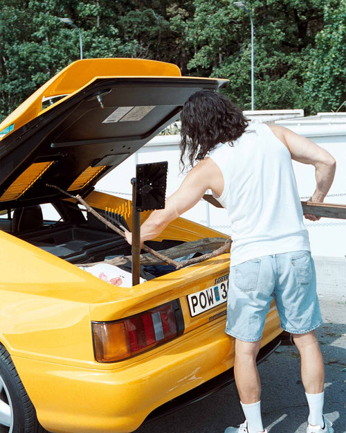 Oskar packing the car trunk wearing Tank Top in White